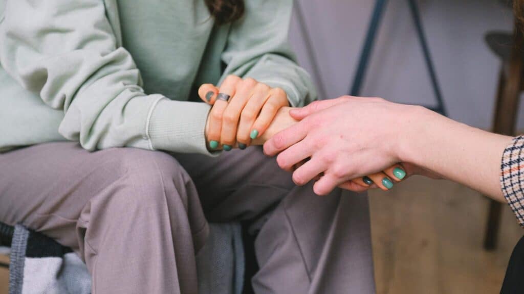 Two people holding hands in a supportive gesture during a counseling session at Recovery Home PA